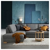 Modern living room with grey SÖRVALLEN sofa, orange throw, guitar, wooden side table, colorful pillows, and blue-green wall.