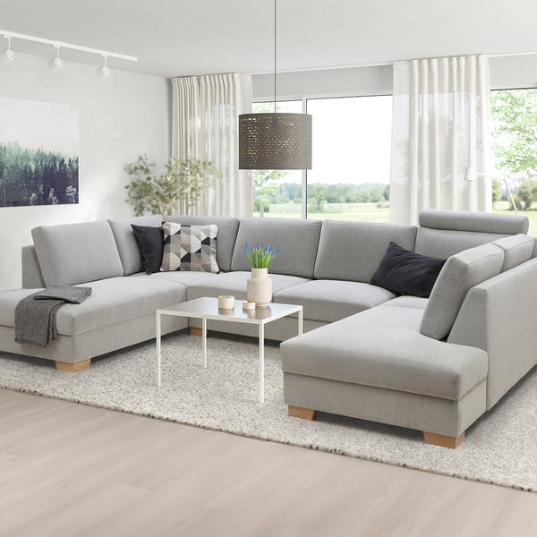 Modern gray u-shaped sofa, large, with chaise lounge, black & white pillows, coffee table, white curtains, natural light.