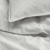 A close-up of neatly folded white and gray striped sheets, showcasing quality stitching and fabric texture.