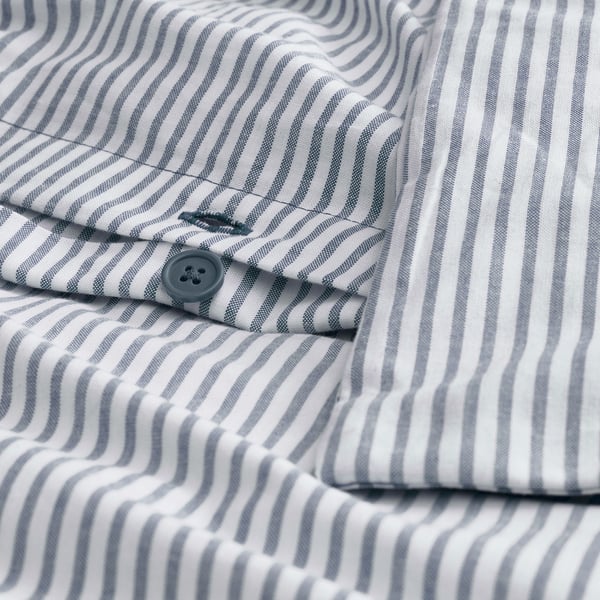 Close-up of striped fabric with blue button and thread detail. Shows high thread count for dense weave.