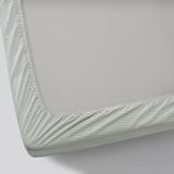 Close-up of high-quality cotton fitted sheet with elastic edges, showing smooth texture and intricate weave.