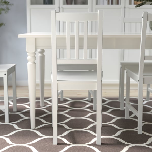 White wooden chairs around a dining table, offering sturdy seating.
