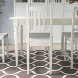 White wooden chairs around a dining table, offering sturdy seating.