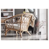 Modern wicker chair in natural color with cushions, placed in a minimalist room.