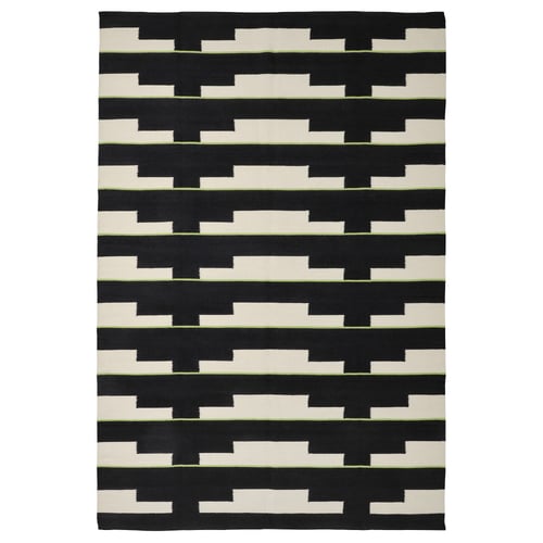 A black and white geometric, handwoven wool rug named STOCKHOLM 2025, featuring a repeating pattern, reversible design.