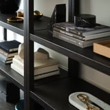 Bookshelf with multiple shelves displaying books and decorative items. Black marbled bookends hold books upright.