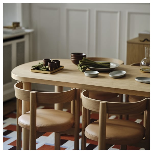 Wooden dining table and chairs with foliage centerpiece, designed for indoor use, seating 6-8.