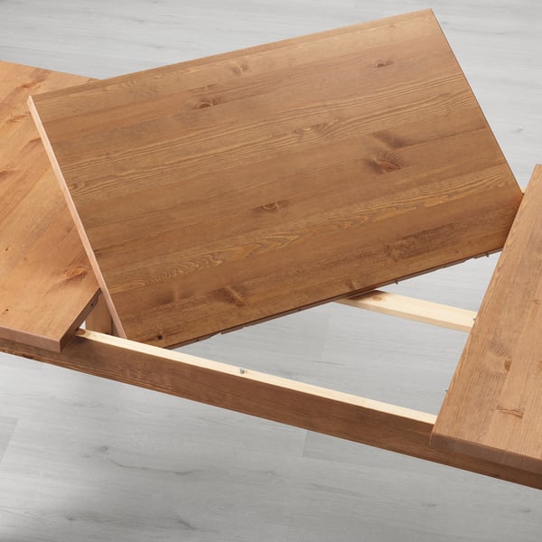 Wooden dining table made of solid pine with an adjustable extension leaf underneath, designed to extend seating from 4 to 6 people.