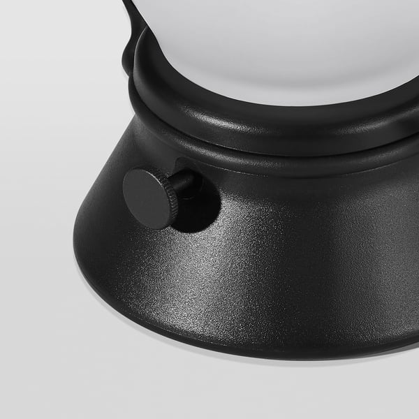 Close-up of black, sleek modern lantern. Rounded design with textured surface and small control dial.