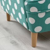Vibrant turquoise chair with white polka dots, sturdy light wood legs, soft cushions, high-quality fabric.