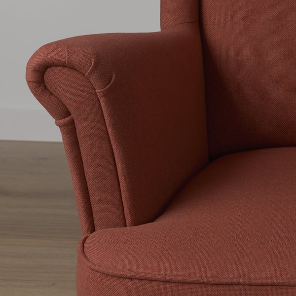 Comfortable red chair close-up, showcasing high back, round armrests, and soft lines.