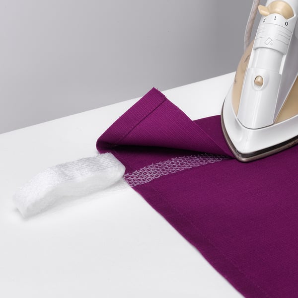 A white iron presses a purple cloth with hemming strips, making it eaSY to hem without sewing.