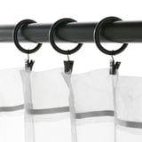 Black curtain rod with three rings and clips hanging sheer curtains. Shows SYRLIG curtain rings dual attachment method with hooks or clips.
