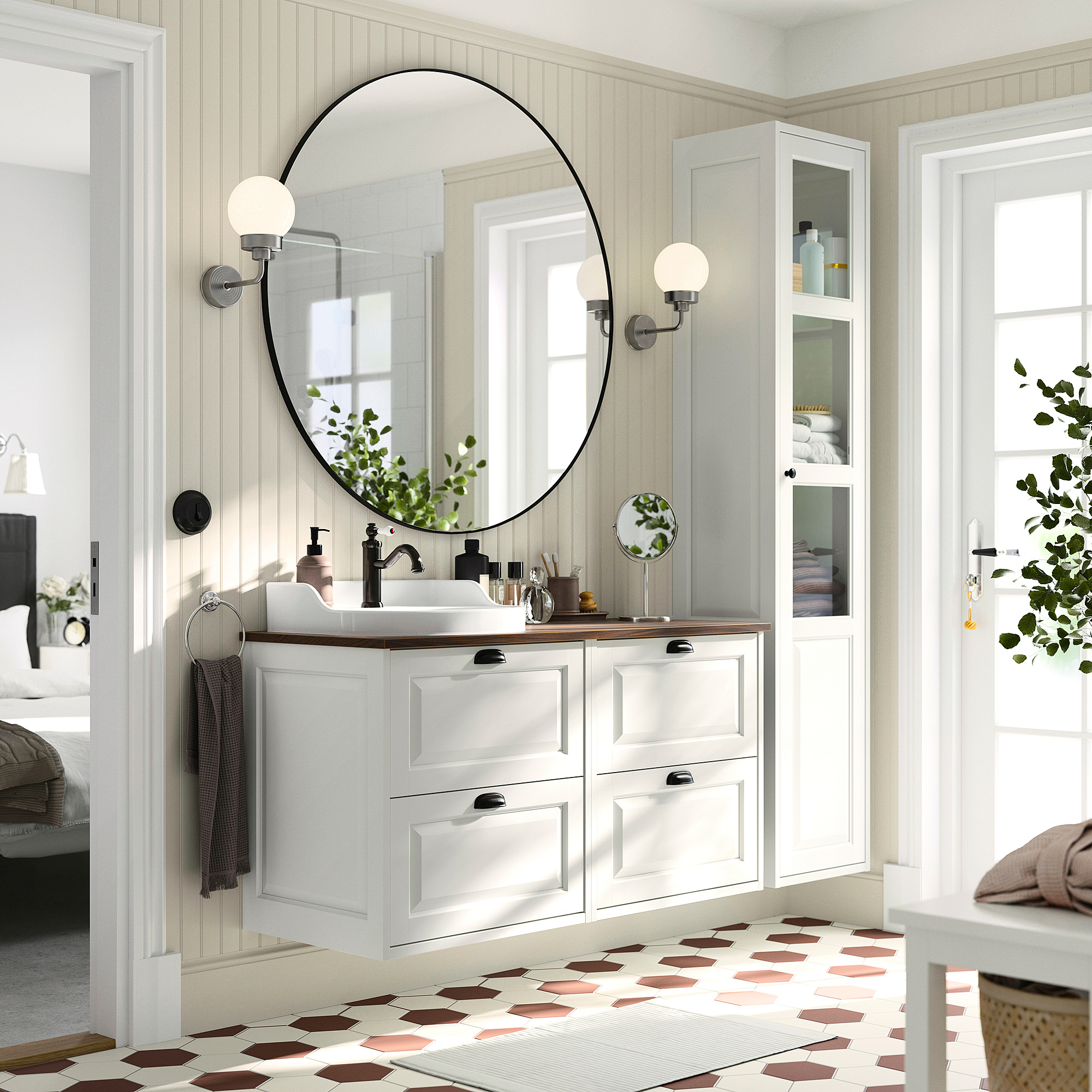 Modern bathroom with white TÄNNFORSEN vanity, wooden top, round mirror, hex tiles, plants, and storage.