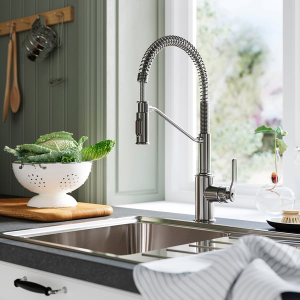 Modern kitchen with TAKSJÖN chrome faucet, sink, and green veggies.