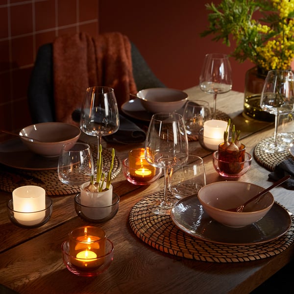 Table setting with TALLTITA tealight holders in amber and clear glass, combining elegant simplicity with warm, inviting ambiance.