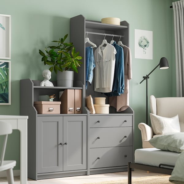 Modern bedroom with gray TJOG storage unit, clothes, plant, and chair.