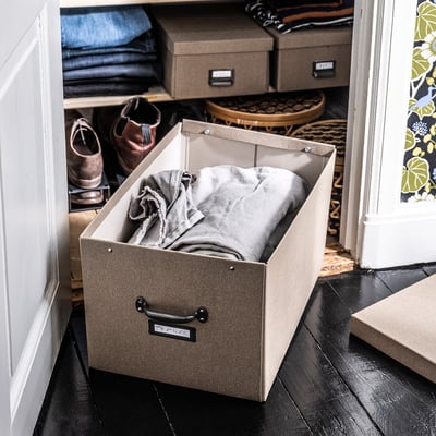Closure box with foldable lid and handle, grey, made of recycled paperboard, stored clothes inside, part of TJOG storage series.