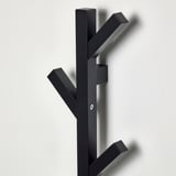 Black wooden coat rack with four hooks, mounted on a wall, showing sturdy construction and clean design for organizing clothes.