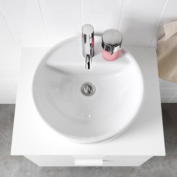 Modern white ceramic washbasin with chrome faucet and drain on a sleek countertop.