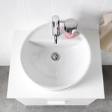 Modern white ceramic washbasin with chrome faucet and drain on a sleek countertop.