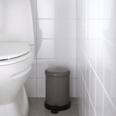 Gray TOFTAN bin with soft-close lid, next to toilet, easy to move & clean.