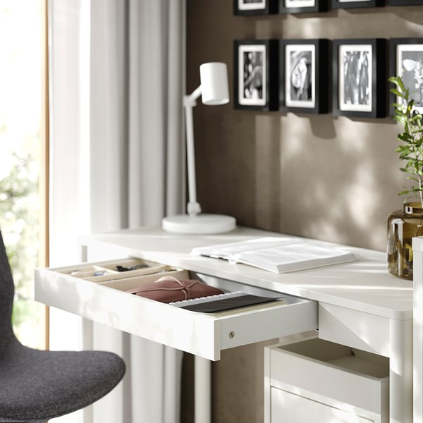 A white desk with an open drawer displaying contents.