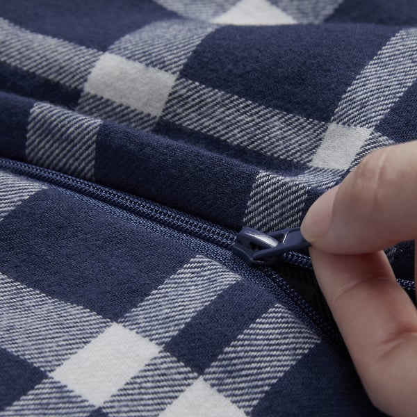 A hand zips a blue and white checkered cotton flannel blanket, showcasing its zipper feature for securing the duvet.
