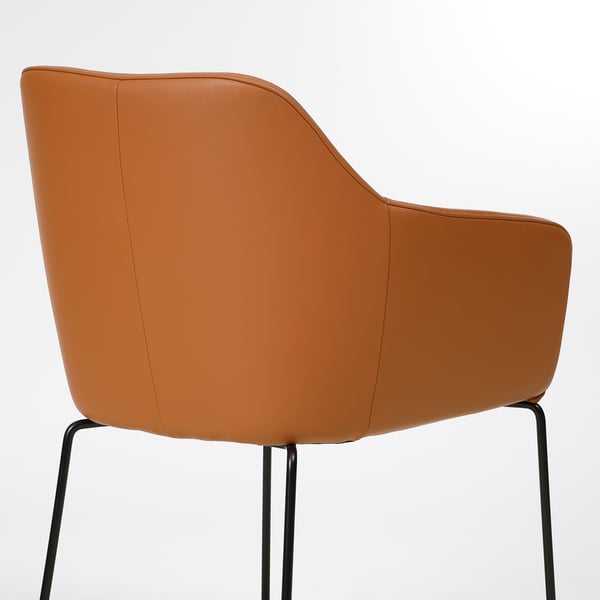 A tan leather chair with curved back and armrests, supported by black metal legs, offering comfort and style.