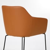 A tan leather chair with curved back and armrests, supported by black metal legs, offering comfort and style.