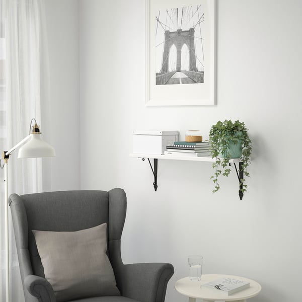 Cozy nook with chair, small table, and wall shelf with decorations and plant.