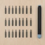 This image shows a TRIXIG black screwdriver set with blue caps laid out on wood. It includes various bits for different tasks.