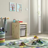 Kids play area with TROFAST toy storage, paintings, and toys on floor.