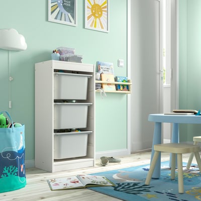 TROFAST white storage drawers, wall-side, toy nearby, on beach rug.
