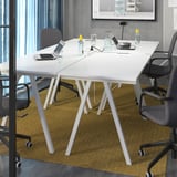 Modern office setup with two white TROTTEN desks, each with a-frame legs, black office chairs, glass bottles, and a wall-mounted tv.