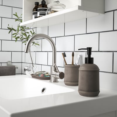 Modern bathroom with TVÅLSJÖN soap dispenser and toothbrush holder on white counter, dark grey, round, stoneware.
