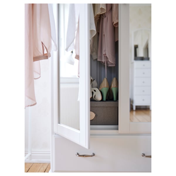 Open white TYSSEDAL wardrobe with hanging clothes, shoes, and drawers, showing organized interior.