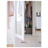 Open white TYSSEDAL wardrobe with hanging clothes, shoes, and drawers, showing organized interior.