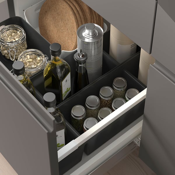 Drawer organizer with compartments, holding bottles, jars, and boxes. Efficient kitchen storage solution.