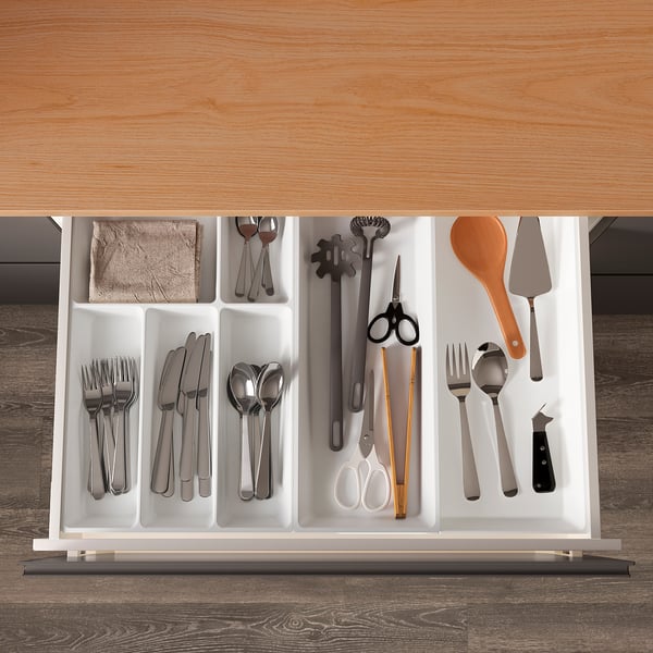 Organized white cutlery tray with various utensils in a drawer.
