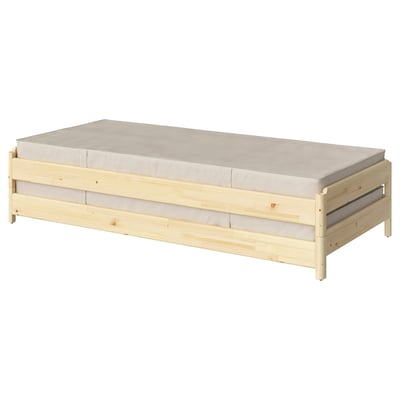 A light wooden stackable bed with a beige mattress, designed for space-saving and versatile use as a sofa or separate beds.