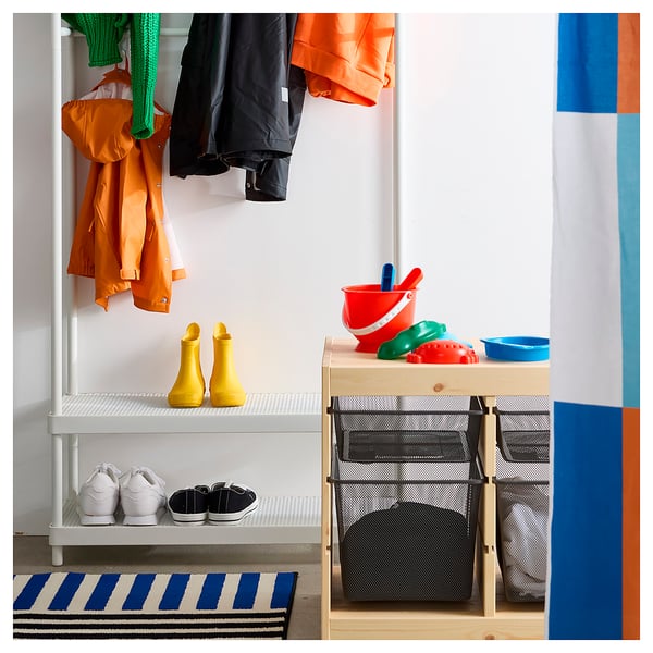 Organized entryway with hanging jackets, yellow boots, white sneakers, black mesh storage, colorful buckets, and striped rug.