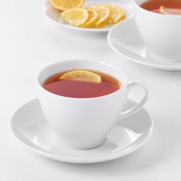 Two cups of tea with lemon slices on a white table. The durable cups are made of feldspar porcelain, suitable for everyday use and gatherings.
