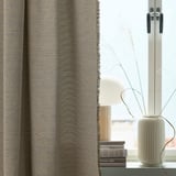 Beige curtain, vase with branches, books - minimalist room decor.