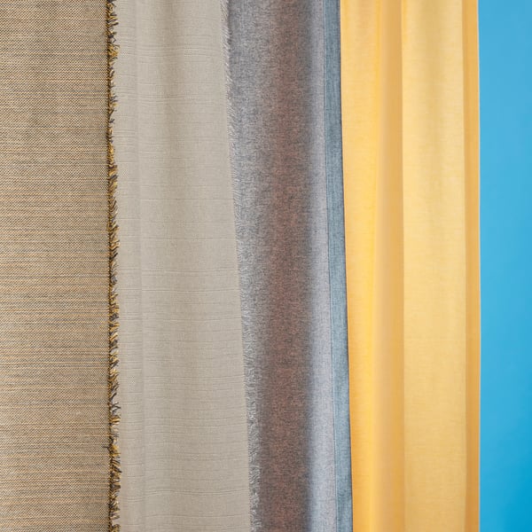 Close-up of VÄXELBRUK curtain with textured stripes in grey, blue, and yellow, fringed edges, against blue background.