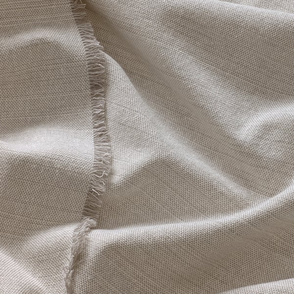 Folded beige fabric with fringed edges, neatly presented, showing texture and quality.