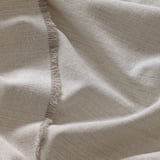 Folded beige fabric with fringed edges, neatly presented, showing texture and quality.