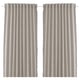 Two beige curtains hang side by side. Made from recycled materials with fringe detailing. Simple, lightweight, and pleated.