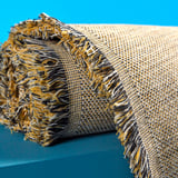 Woven throw with fringes on teal background. Yellow, blue, grey threads. Soft, warm texture.
