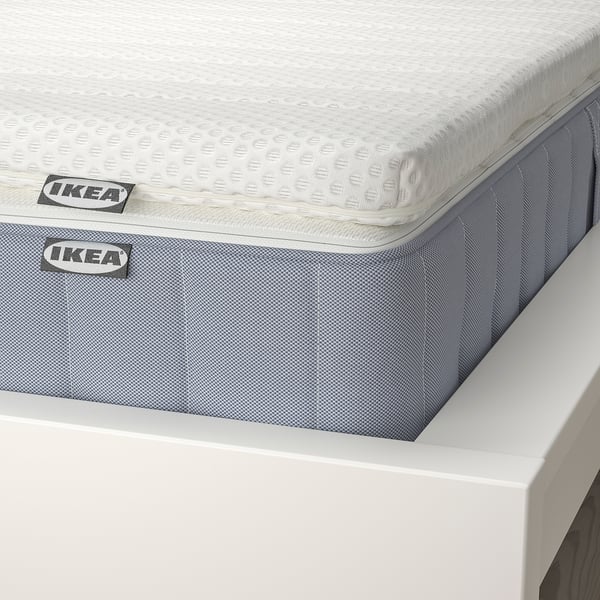Close-up of ikea mattress; shows pocket springs, textured fabric, and brand labels.